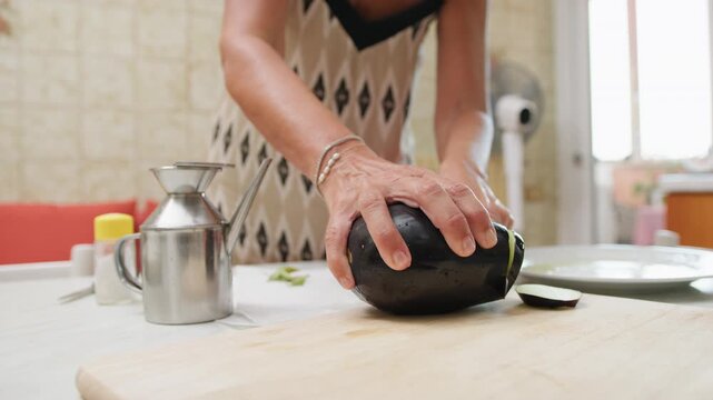 A woman cuts homemade eggplants on a cutting board to make Sicilian parmigiana