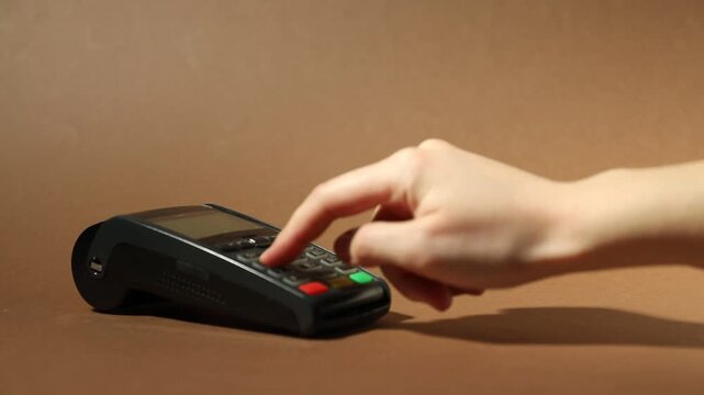 Woman with credit card using payment terminal on brown background, closeup