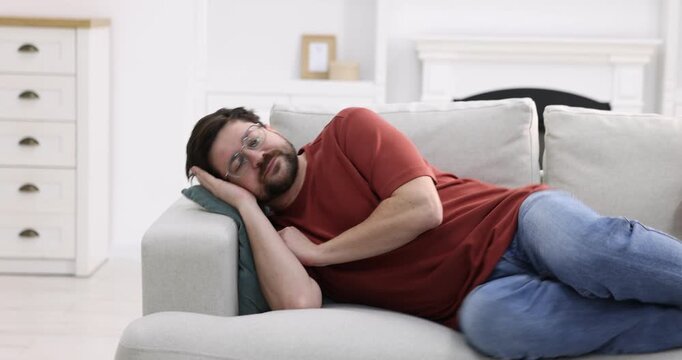 Unhappy man feeling fatigue on sofa at home