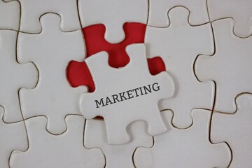 Fototapeta premium white puzzle piece labeled MARKETING sits among others on a red background, symbolizing strategic thinking and collaboration.
