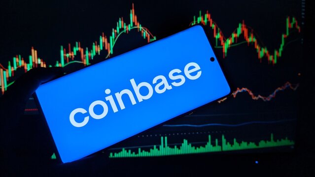 Coinbase logo on smartphone screen with stock market charts in background