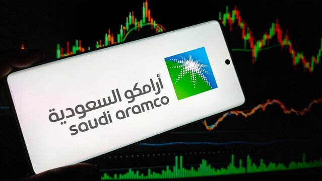 Saudi Aramco logo on smartphone screen with stock market graph background