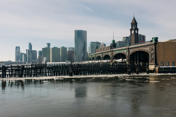 Obraz premium City skyline over calm water with pier and clock tower in the foreground during a sunny day