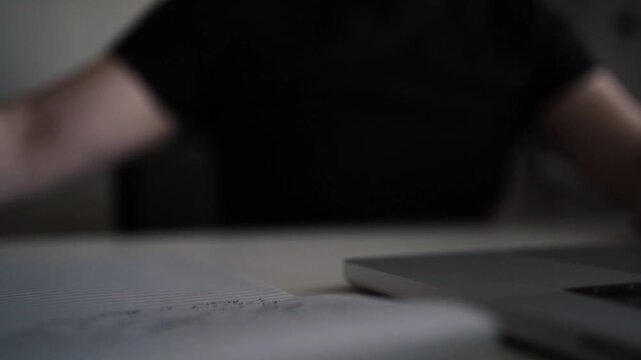 Taking Notes on Paper Notebook While Working on Laptop