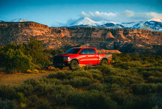 Red off-road pickup truck on desert terrain in Sand Flats recreation area near Moab, Utah