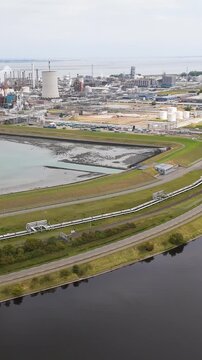 industrial pier pipeline bridge stretch across calm waters skyline distillation towers cooling chimneys defines petrochemical complex netherlands long chemical factories dow chemicals terneuzen 
