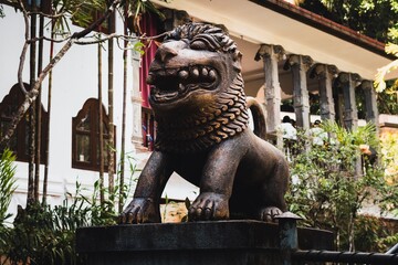 Majestic stone lion statue with intricate details in a garden setting, symbolizing strength and protection.