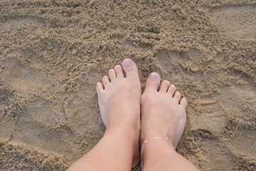 Relaxing at a resort with feet in the warm sand by the sea during a bright sunny day