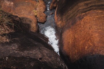 A narrow stream flows between , reddish-brown rocks