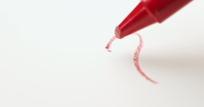 Red crayon drawing a small heart. Sketching a red heart showing love and kindness of a child through coloring. Childs drawing a heart for a loving Valentine's day, or a Father's or Mother's day card.