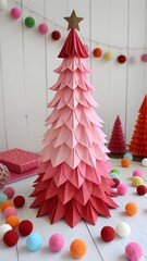 Handmade paper Christmas tree in shades of pink and red. surrounded by colorful pom-poms and