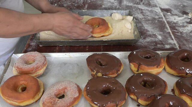 BAKER ADDING SUGAR TO DONUTS