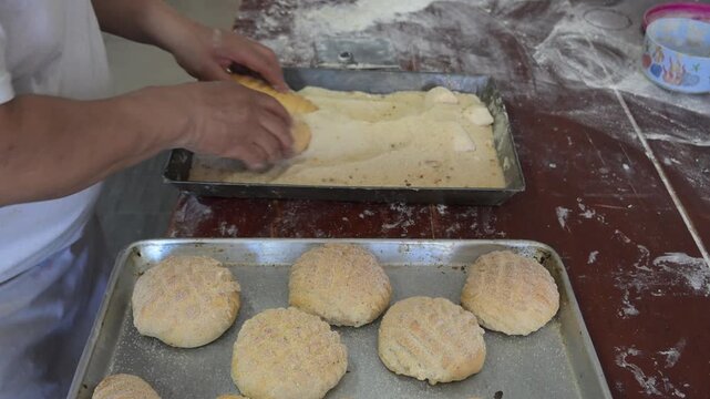 BAKER PLACING SUGAR ON A SWEET BREAD CALLED A WORM