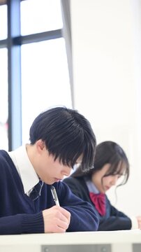 学校や塾などで受験対策の模試のテストを受ける日本人の高校生の男女の縦動画