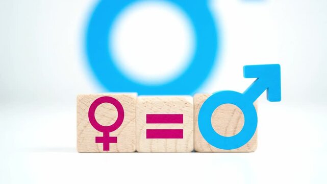 Close-up of wooden blocks with gender equality symbols on a white surface with a blurred background.