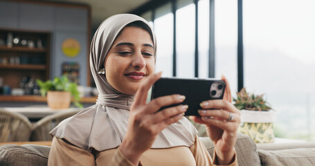 Fototapeta premium Muslim woman, phone and streaming in lounge for movie, subscription app and watch series for entertainment. Drama film, video platform and happy person with hijab in home, mobile and relax on weekend