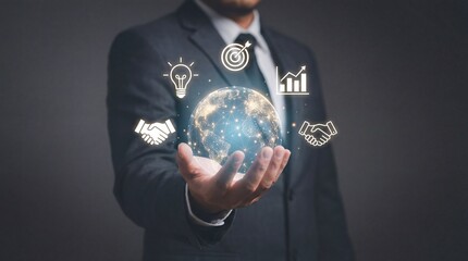 Businessman holding a glowing globe with partnership and growth symbols surrounding it on dark background
