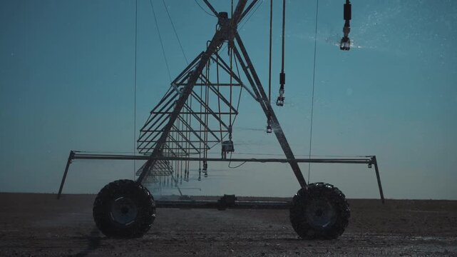A modern center pivot irrigation system operating on an open agricultural field. Sprinkler nozzles evenly distribute water across the soil surface, ensuring optimal moisture levels.