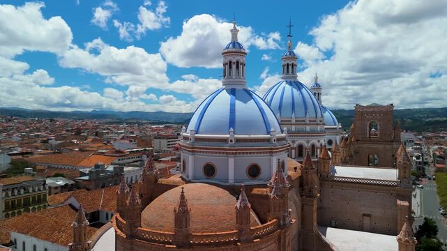 Cinematic drone parallax shot orbits the three massive glazed-tile domes of the Cathedral of the Immaculate Conception, showcasing their intricate blue and white patterns against the Andean skyline