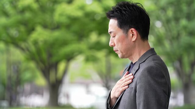 Dignified anonymous individual in dark suit jacket, hand over heart, side profile, soft focus, blurred background, slow dolly video. Concept of respect, gratitude, remembrance