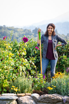 Young woman holding shovel in her beautiful garden