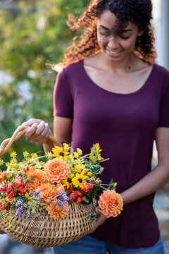 Woman holding basket of fresh cut garden flowers in garden