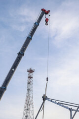 Large Construction Crane Lifting Steel Structure Against Cloudy Sky