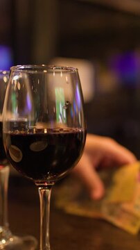 Close Up of Hand Picking Up Lottery Tickets Behind Red Wine