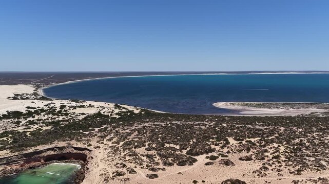 4K aerial drone view of Great Australian Bight coastline, jetty, caravan park, turquoise ocean, sand dunes, white sand beach and limestone cliffs (Fowlers Bay, South Australia)
