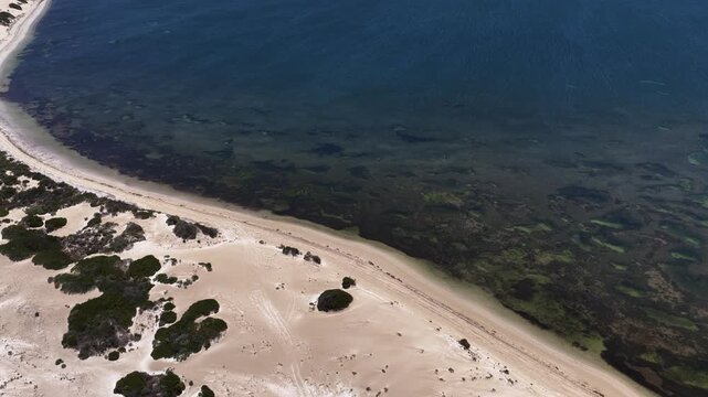 4K aerial drone view of Great Australian Bight coastline, jetty, caravan park, turquoise ocean, sand dunes, white sand beach and limestone cliffs (Fowlers Bay, South Australia)