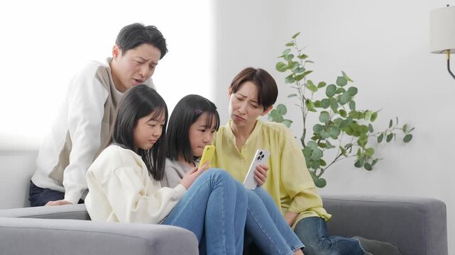 スマホを見ながら困った表情の小学生の女の子の家族