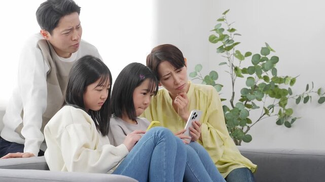 スマホを見ながら困った表情の小学生の女の子の家族