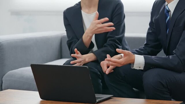 ロビーでノートパソコンを見ながら会話する男女ビジネスパーソンのグループ