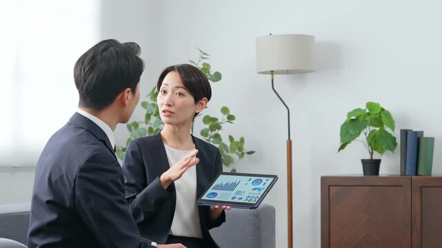 ロビーでタブレットを見ながら商談する男女ビジネスパーソンのグループ