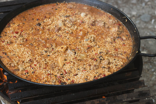 Traditional Spanish paella cooking in pan over open fire