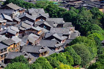 Fototapeta premium The entire Thousand-Household Miao Village is nestled among lush green mountains and clear waters, showcasing the harmony between the traditional stilted houses and pristine natural landscape.