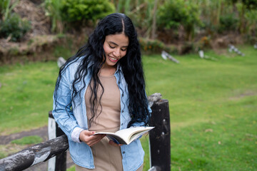Young woman enjoying reading book outdoors in nature