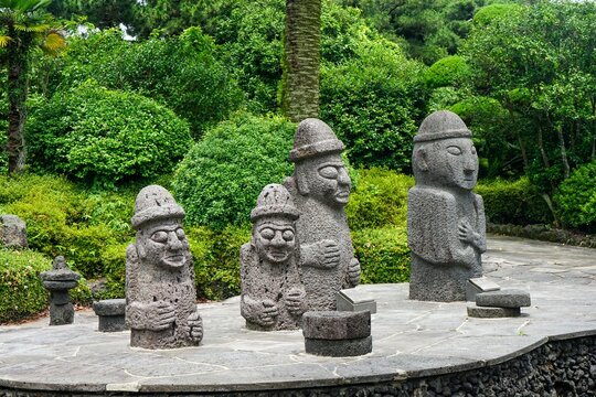 Several stone grandfather statues on Jeju Island in South Korea with forest in background