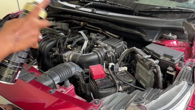 The process of cleaning the car engine compartment by spraying foam liquid into the dirty and dusty engine compartment.
