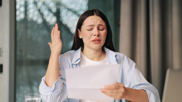 Distressed woman reads important document, experiencing deep worry. Reacts with frustration and sadness to bad news. Difficult situation conveyed through emotional response, significant problem.