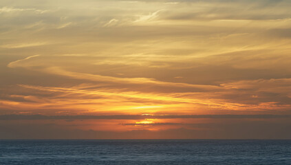 Fototapeta premium Serene sunset over calm sea with golden clouds and tranquil horizon