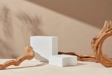 White podium blocks with wooden branches in a warm pastel background for product presentation