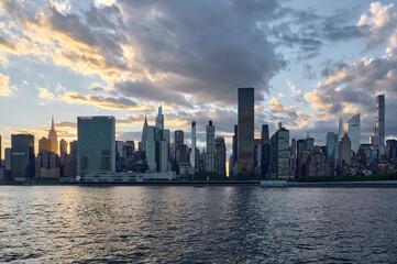 Obraz premium New York City Manhattan skyline at sunset with skyscrapers reflecting over the river under a colorful sky