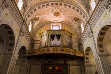 Obraz premium Elaborate wooden pipe organ and decorated balcony inside the Cattedrale dell'Immacolata Concezione in Bosa, Sardinia. Warm daylight streams through arched windows, highlighting intricate architectural
