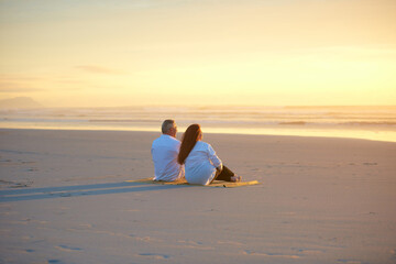 Fototapeta premium Back, love and sunset sky with couple on beach together for anniversary, bonding or relationship. Ocean, scenic view and space with mature people on sand at coast to relax for security or trust