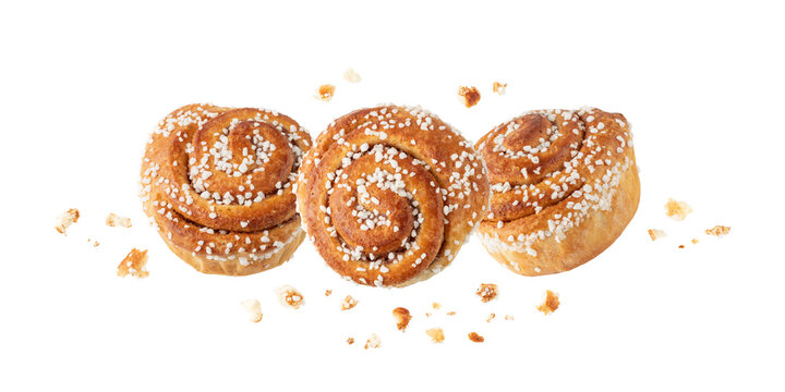 Fresh baked three cinnamon buns with crumbs flying isolated on white background. Traditional swedish sweet pastry kanelbulle.