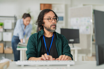 cheerful Asian man smiles while holding a takeaway coffee cup at his desk in a modern office, enjoying a relaxing break during work, showing positive energy, professional lifestyle, and casual work © whyframeshot