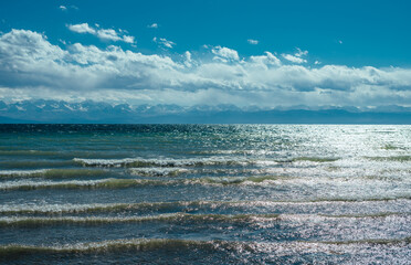 Waves on Issyk-kul lake in Kyrgyzstan, view with clouds and mountains