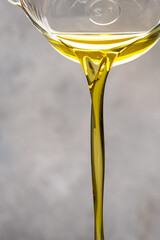 Olive oil flowing to the bowl on the white stone background