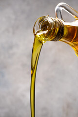 Organic olive oil pouring from carafe on vintage stone background
